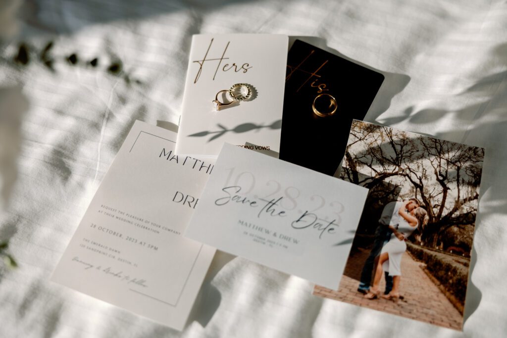 Destin, FL beach elopement wedding flat lay with invitations, engagement photo, vow books and rings