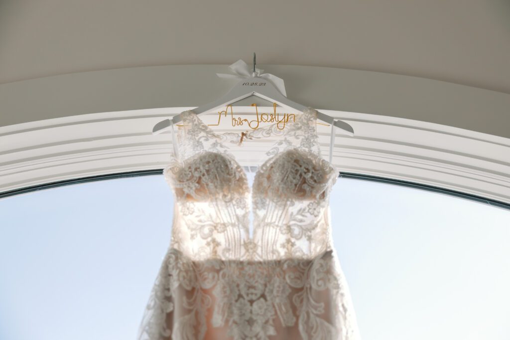 Bridal gown hanging in large window of a luxury bedroom for a beach elopement wedding in Destin, FL