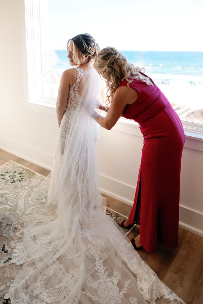 Mother of bride helping her into her bridal gown in a luxury beach house in Destin, FL
