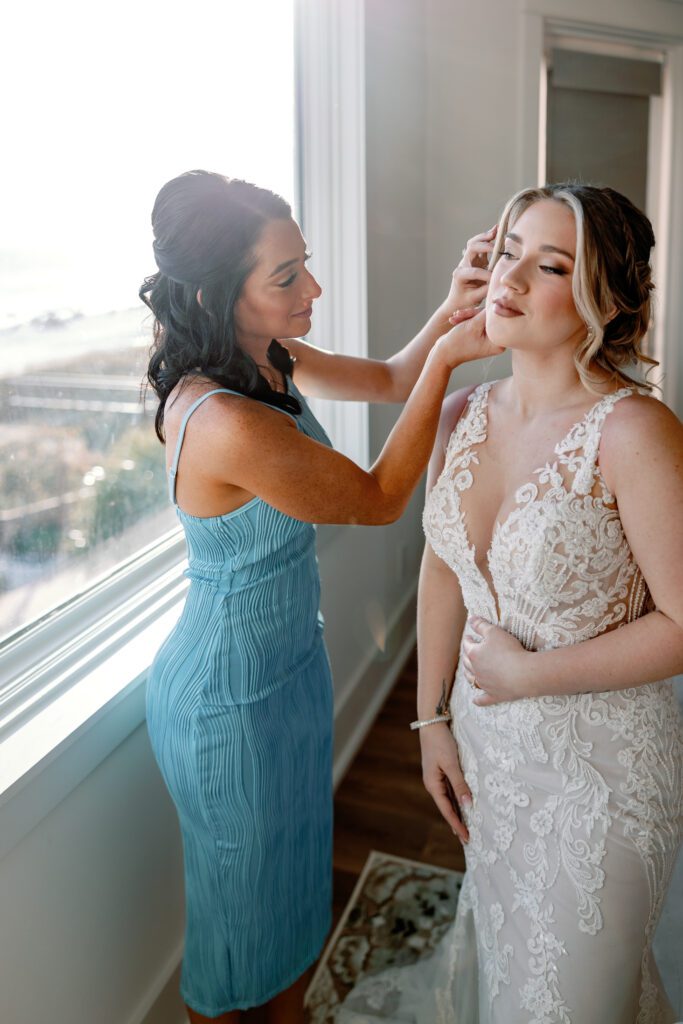 Maid of Honor helping the bride put on earrings in a luxury beach house in Destin, FL
